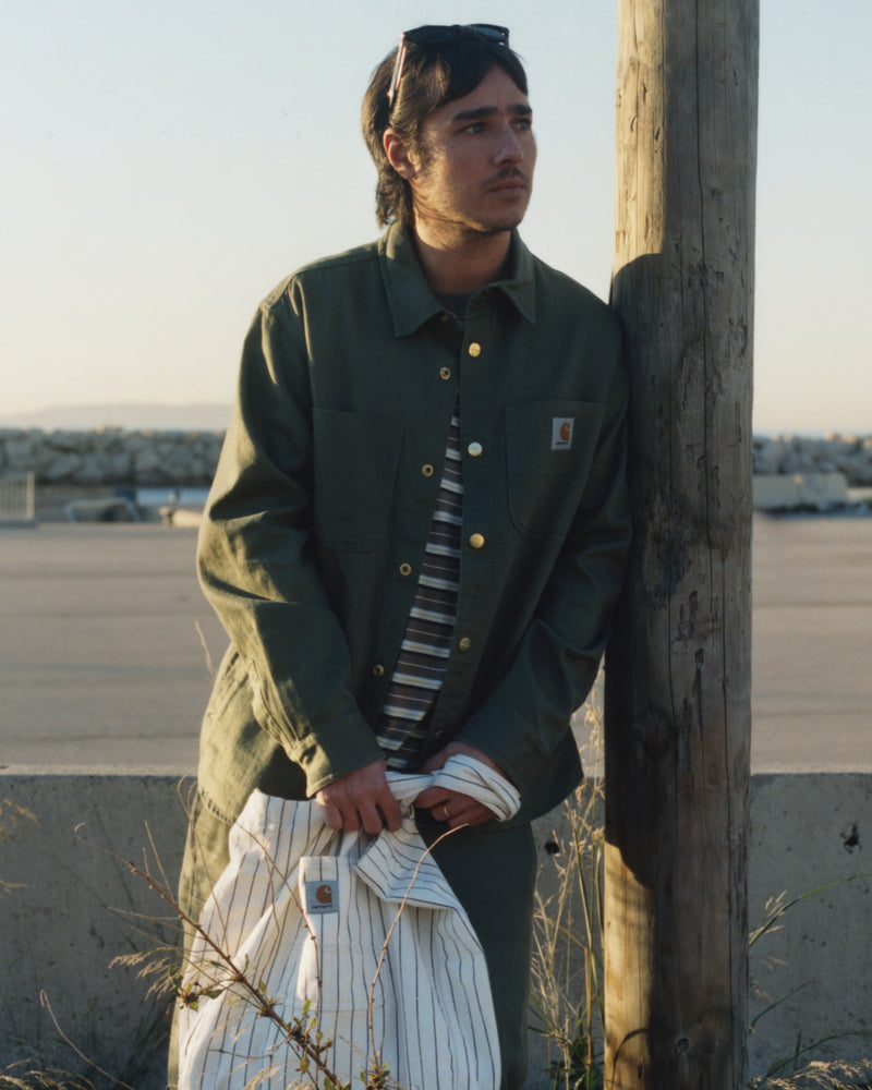 Model leaning on pole wearing a Crawford Shirt Jacket in Dollar Green